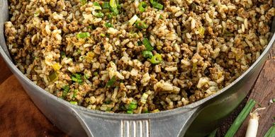 Close-up of cooked ground meat with herbs in a metal bowl.