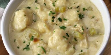 A bowl of creamy chicken and dumplings garnished with parsley.