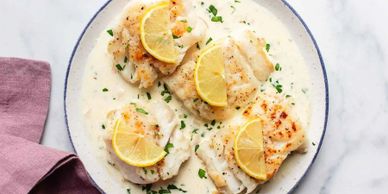 Pan-seared fish fillets with creamy lemon sauce and parsley garnish.