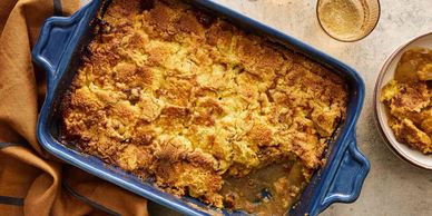 Golden baked apple cobbler in a blue ceramic dish with a serving on the side.