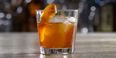 A classic whiskey cocktail garnished with an orange peel in a glass.