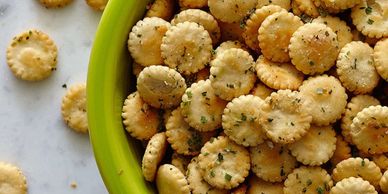 Bowl of round herb-seasoned crackers on a marble surface.