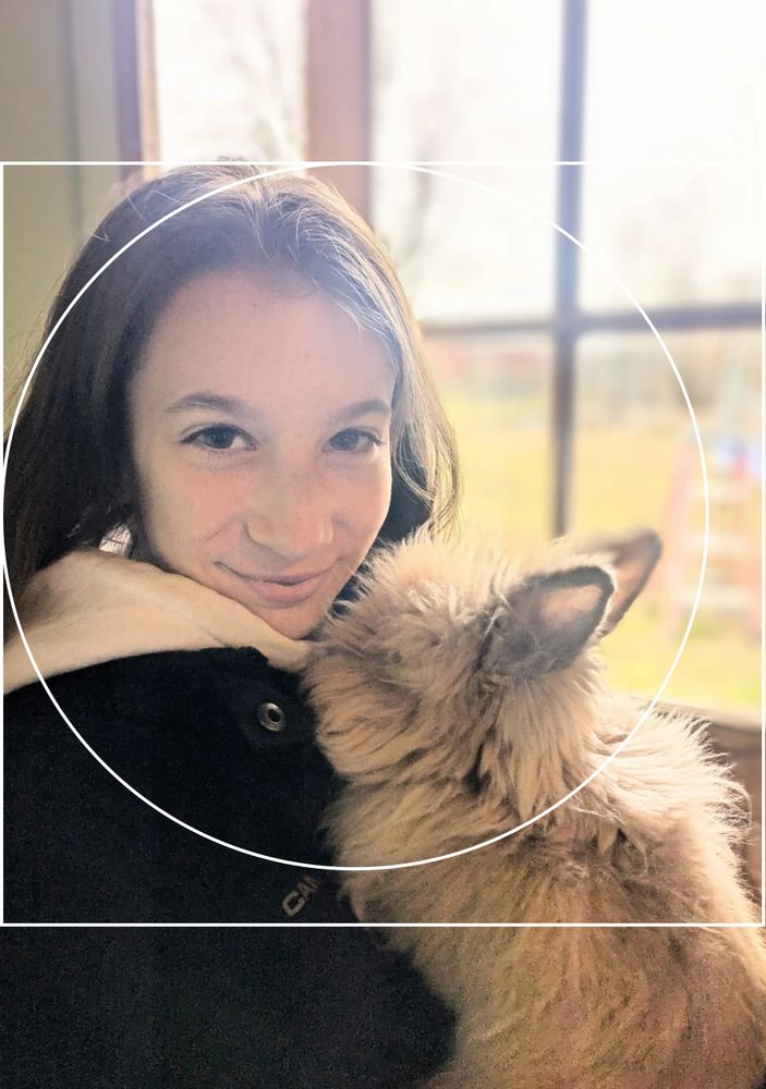 A girl smiling with a fluffy bunny nuzzling her face.