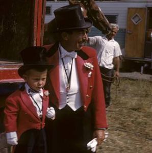 Man and boy in red formal jackets and top hats.