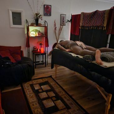 Dimly lit room with a person lying face down on a massage table.