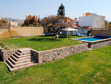 A backyard with a swimming pool, trampoline, and stone steps.