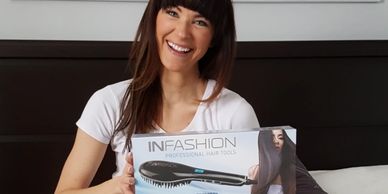 Woman holding up a heat tool that straightens hair while brushing. 