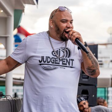 Dj Judgement passionately singing into a microphone at an outdoor event.
