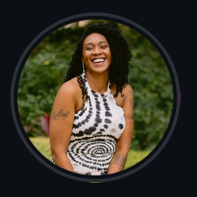 Smiling woman in a black and white tie-dye dress outdoors.