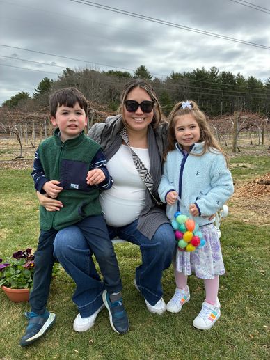 A woman with two children posing outdoors on a cloudy day.