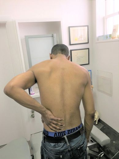 Man holding his lower back in a clinical setting.