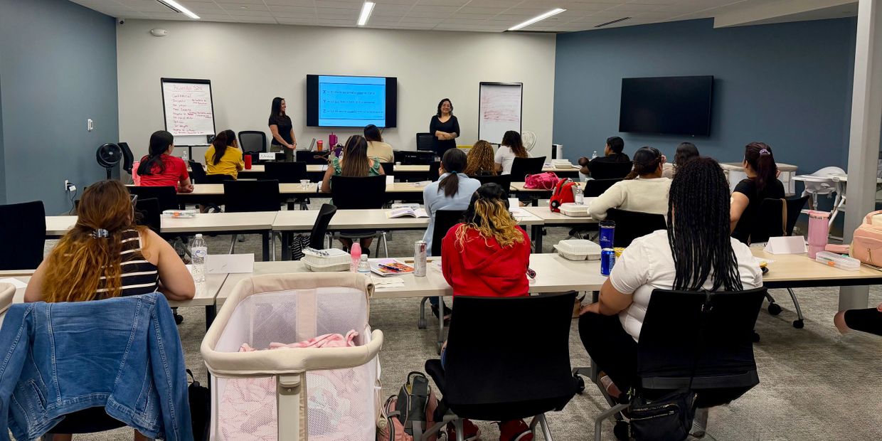 A classroom setting with students listening to two instructors at the front.