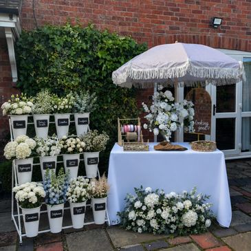 Elegant outdoor wedding flower arrangement with labeled bouquets and a decorated table.