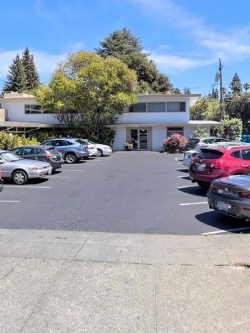 Parking lot in front of a modern building with cars parked on both sides.