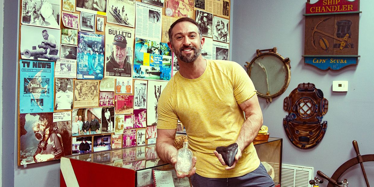 Man in yellow shirt holding artifacts in a maritime museum.
