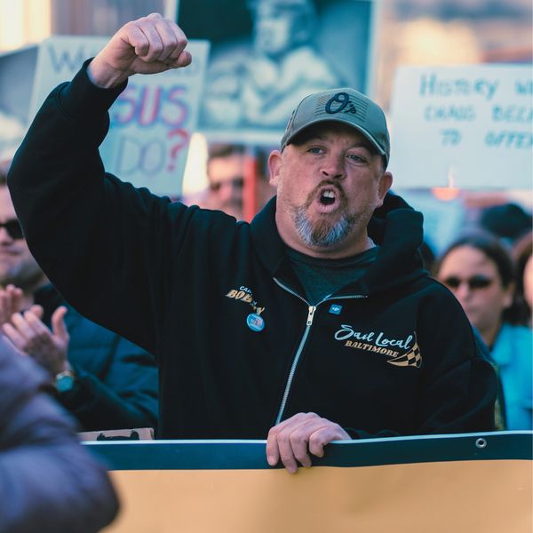 Man passionately protesting with raised fist in a crowd.