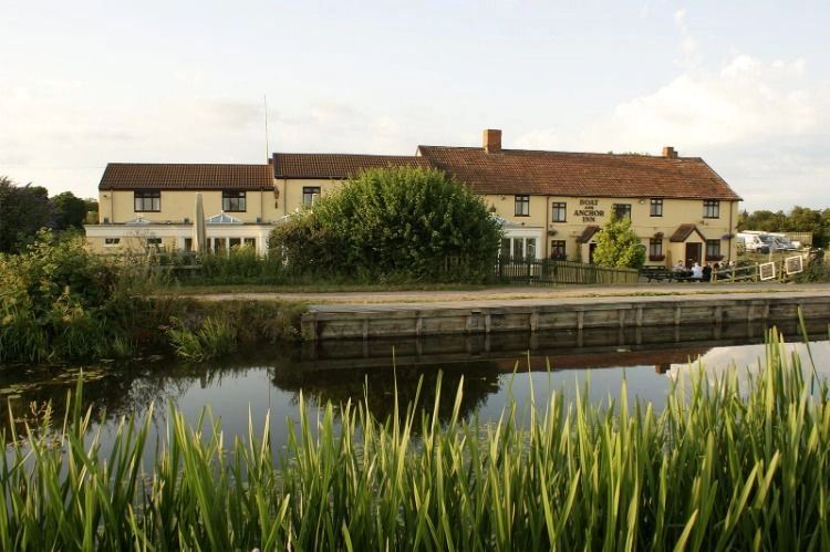 A peaceful inn by the water with greenery and a wooden dock.