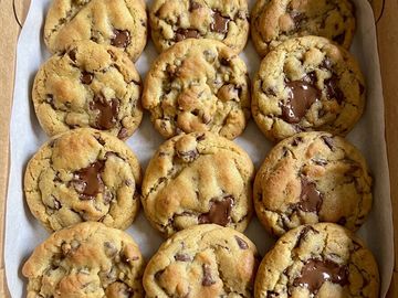 Freshly baked chocolate chip cookies on parchment paper.