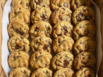 Freshly baked chocolate chip cookies arranged in neat rows.