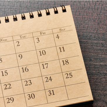 A wooden spiral-bound calendar showing dates from Wednesday to Saturday.