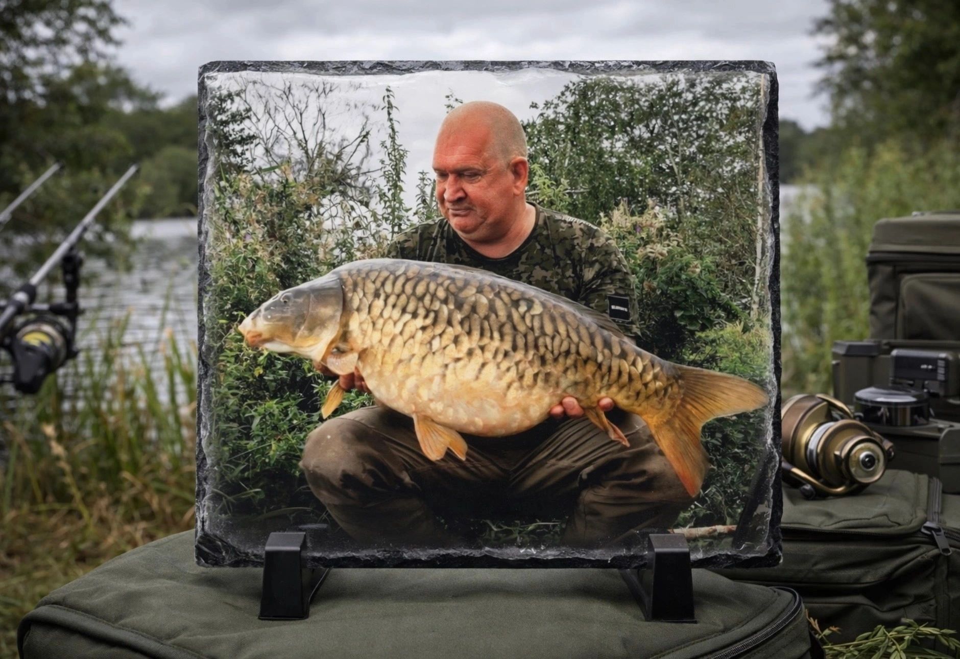 A man holding a large fish outdoors by a lake, captured in a photo frame.