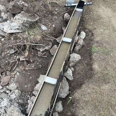 Concrete being poured into a long wooden form for a foundation.