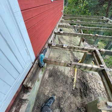 Wooden framework being constructed beside a red house exterior.