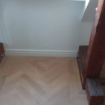 Wooden beams supporting a ceiling in a room with light flooring.
