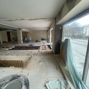 Interior of a building under renovation with exposed floors and construction materials.