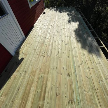 Newly installed wooden deck attached to a red house with shoes visible at the bottom.