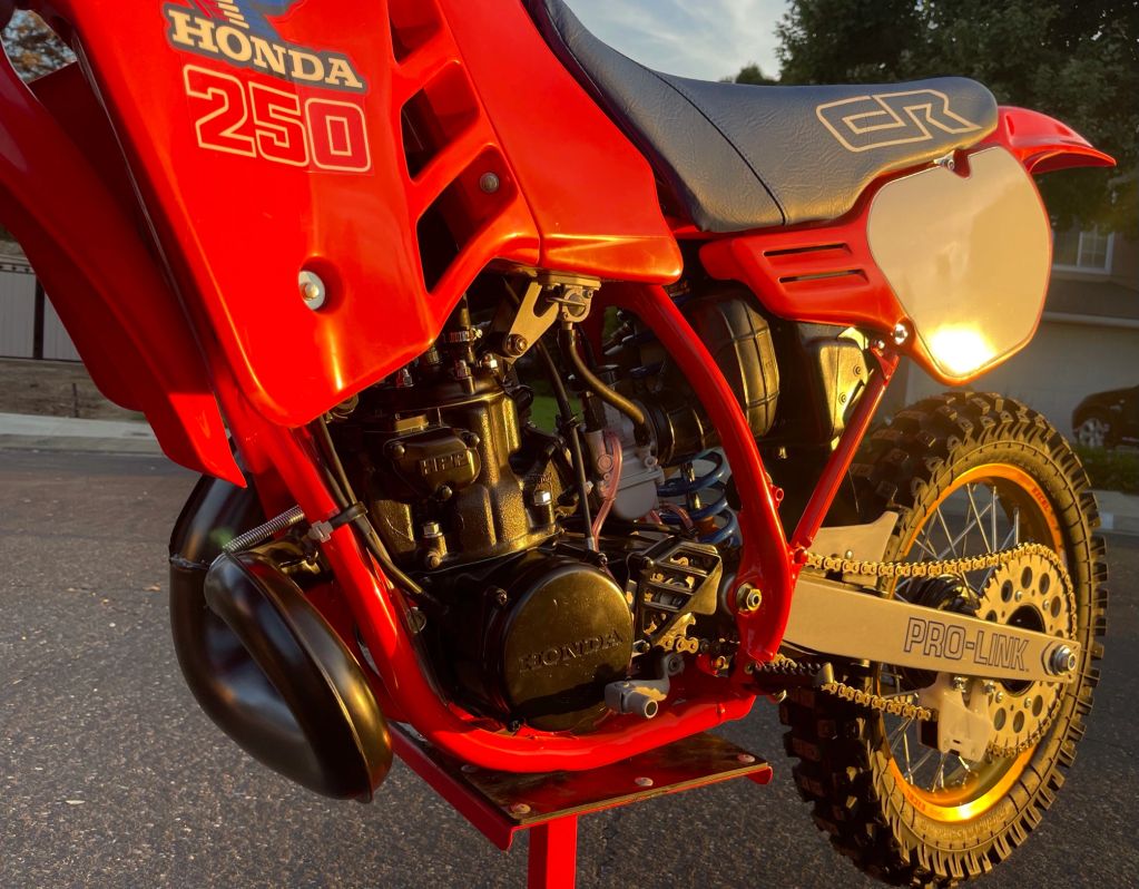 Close-up of a red Honda 250 dirt bike engine and rear wheel.