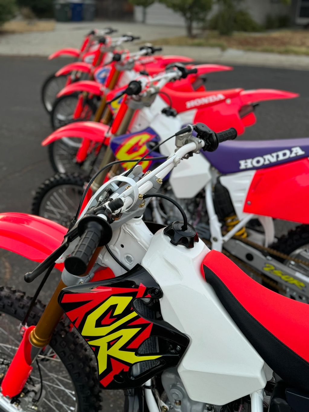 Lineup of red and white Honda dirt bikes with vibrant graphics.