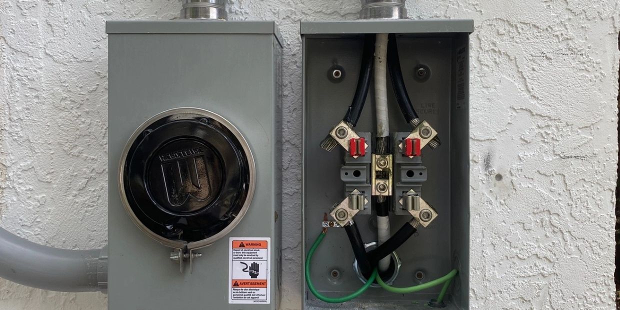 Two electrical boxes on a textured white wall, one open showing wiring.