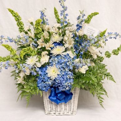 Elegant blue and white floral arrangement with green foliage in a white basket.