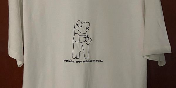 White T-shirt with a minimalist line drawing of a couple hugging and text.