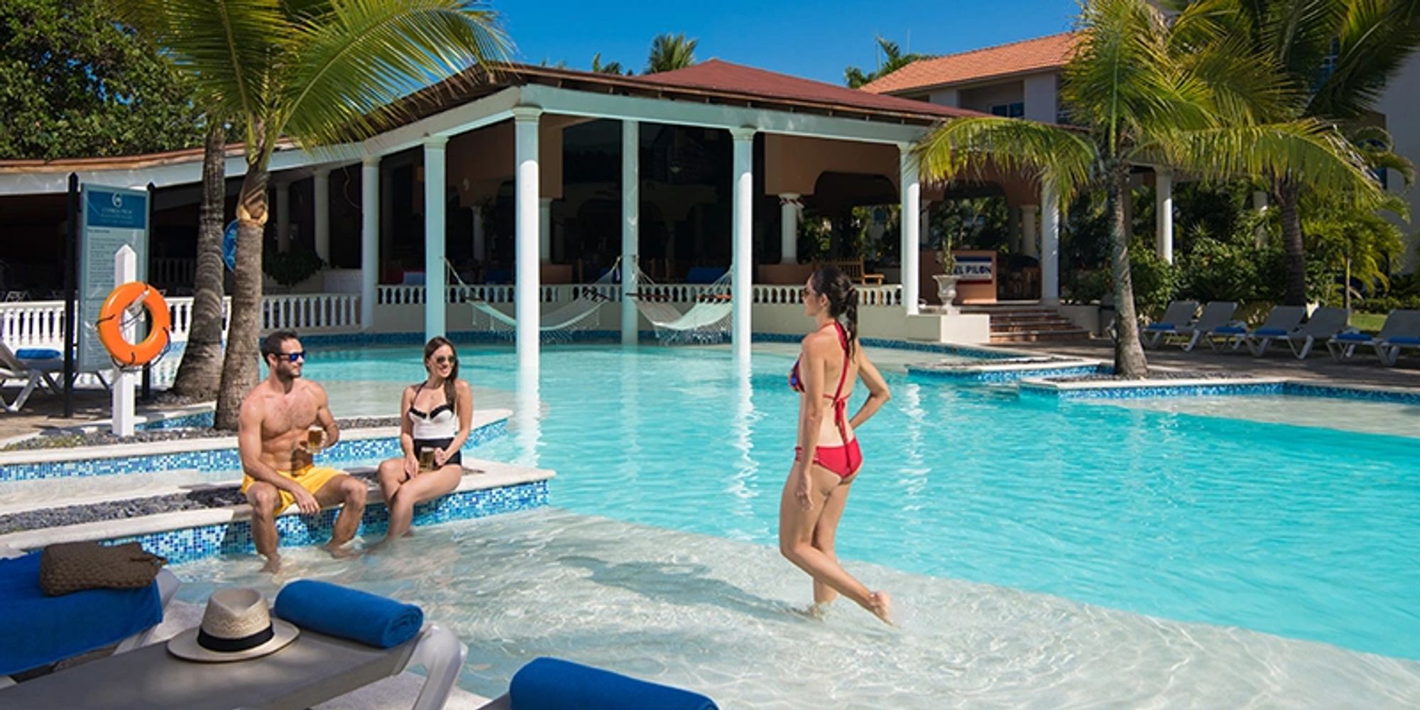 People enjoying a sunny day by the pool at a tropical resort.