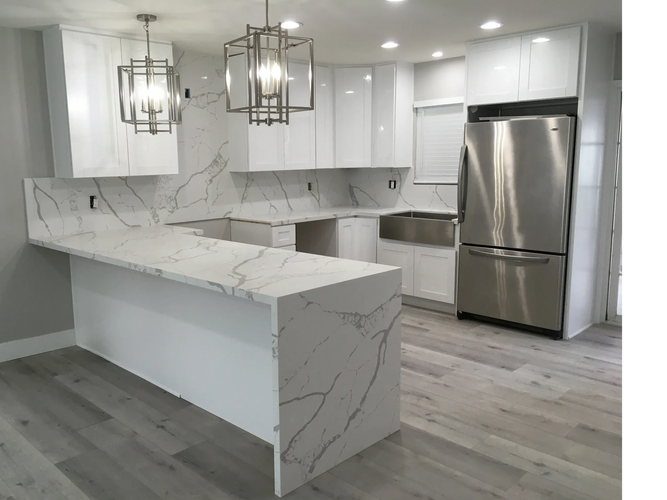 Modern kitchen with white marble countertops and stainless steel appliances.