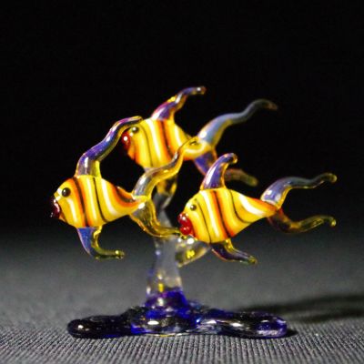 Glass sculpture of three yellow and striped fish.