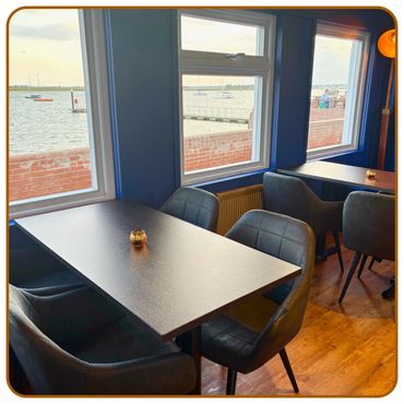 Cozy dining area with sea view through large windows and modern chairs.