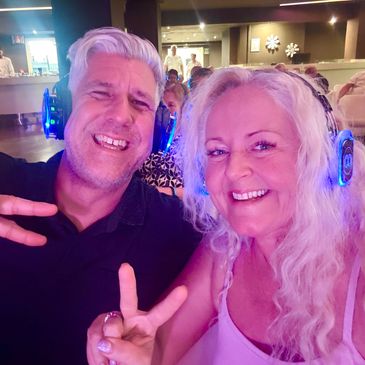 Two people wearing headphones and smiling at a social event.