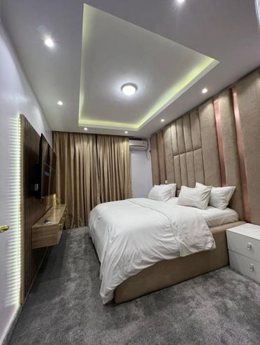 Modern bedroom with soft lighting and a large bed.