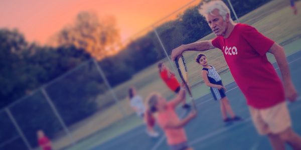 Tennis coach teaching students how to volley in Seaside, Florida.