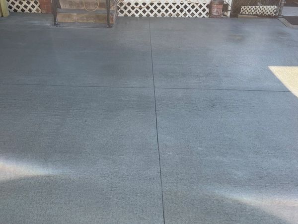Smooth concrete driveway with lattice fence in background.