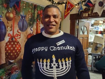 Man wearing a festive Happy Chanukah sweater with a menorah design.