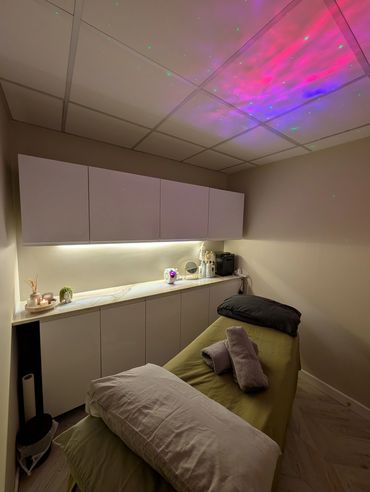 Cozy spa room with massage table and ambient lighting.