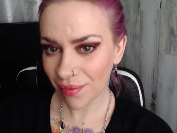 Woman with purple hair and nose ring posing for a close-up selfie.
