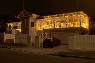 Warm white roofline and balcony lighting with cascading fairy lights, for magical Christmas lights.