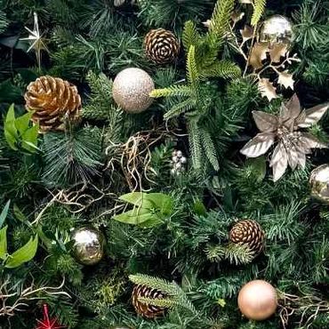 Dense greenery backdrop styled with gold ornaments, pinecones, and subtle decorative accents.
