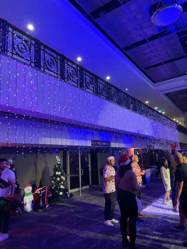 Vertical fairy light curtain with overhead wash lighting, creating a full ambient glow for event.