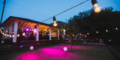 Large outdoor party featuring festoon lighting and pin floodlighting on ground.